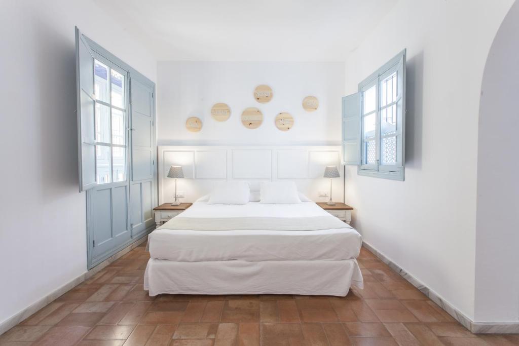 塞维利亚圣克鲁兹套房公寓酒店的一间白色卧室,配有两张床和两个窗户