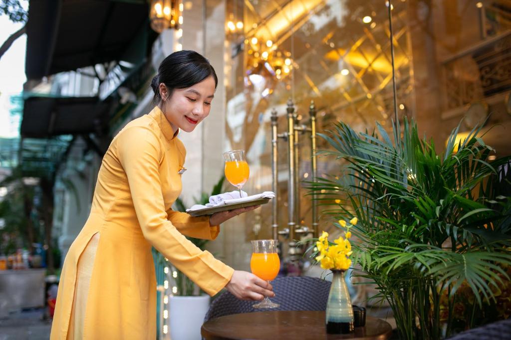河内Hanoi Diamond King Hotel & Travel的穿着黄色衣服,拿着一盘食物的妇女