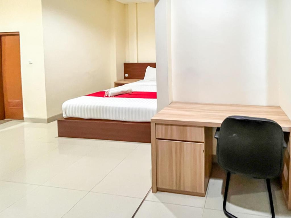 特尔纳特岛RedDoorz Plus @ Grand Tabona Hotel Ternate的一间卧室配有一张床、一张桌子和一把椅子