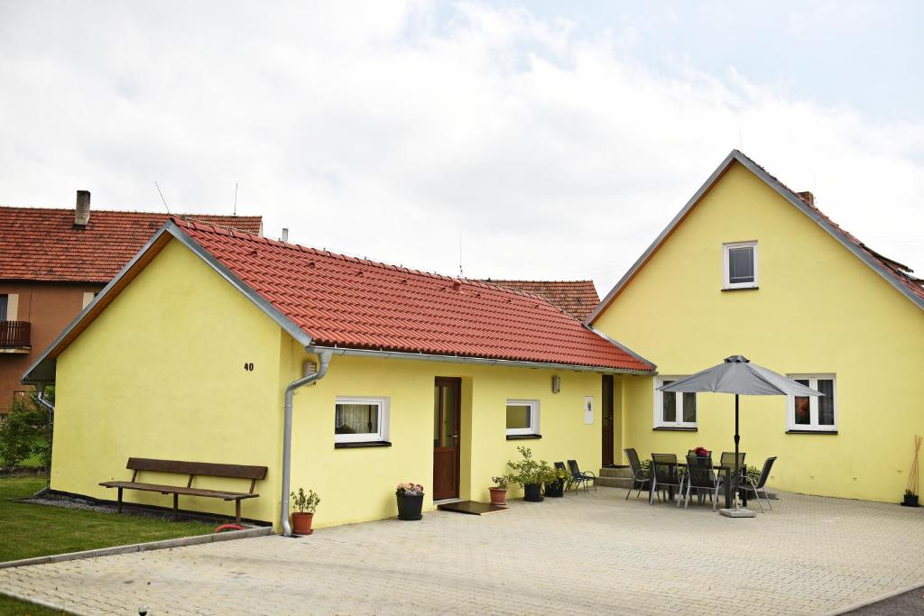 PřísečnáPenzion Rozárka的黄色的房子,配有桌子和雨伞