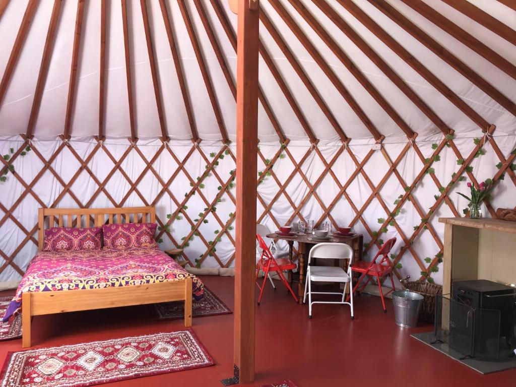新港The Yurts at Burnt House Farm的蒙古包内一间卧室,配有一张床和一张桌子
