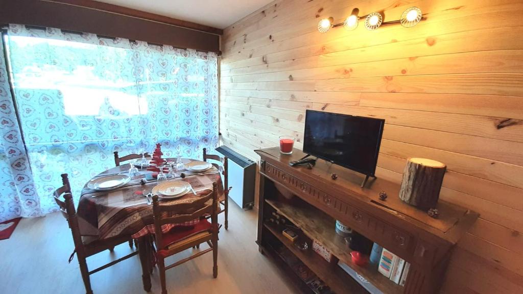 梅塔比耶Au Doubs Refuge的用餐室配有一张桌子、一台电视和木墙