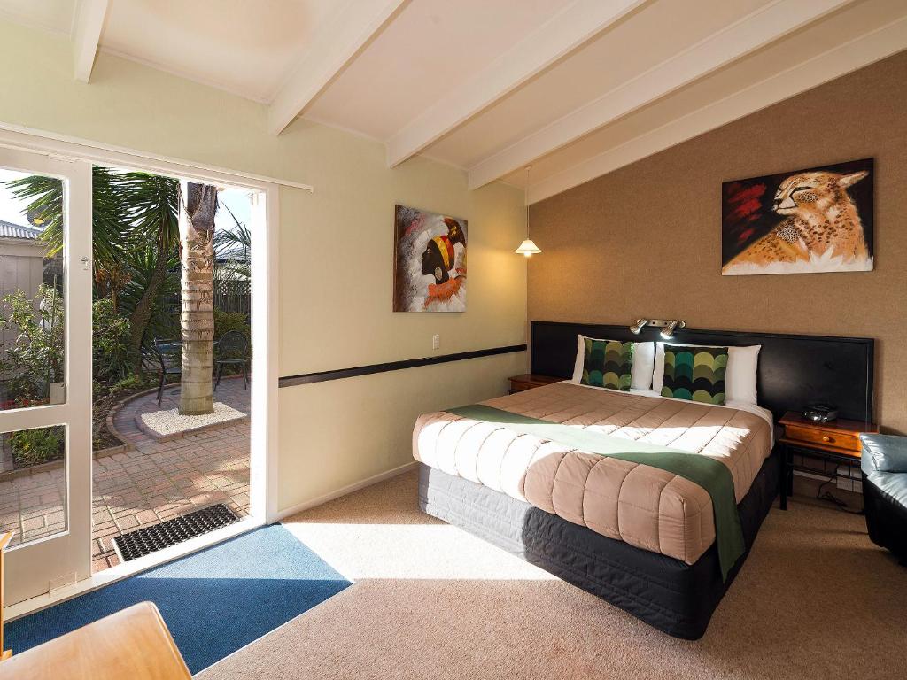 罗托鲁瓦MALFROY Motor Lodge Rotorua的一间卧室设有一张床和一个滑动玻璃门