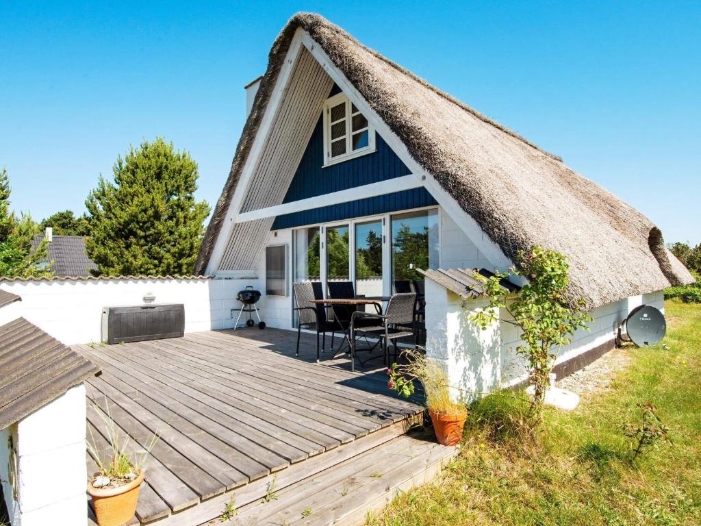灵克宾Holiday Home Strandgårdsvej III的茅草屋顶小屋 - 带木甲板