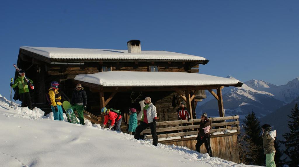 阿尔卑巴赫Hütte - Ferienhaus Bischoferhütte für 2-10 Personen的一群人站在小屋外的雪中