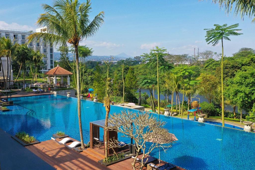 Padalarang万隆梅森青松酒店的一座棕榈树大型游泳池和一座建筑