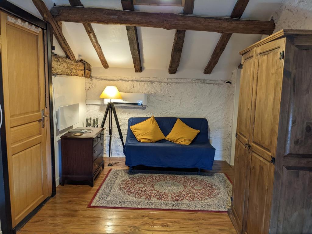 Buzet-sur-BaïseGîte L'Ancienne Charcuterie的客房内的蓝色沙发,配有两个黄色枕头