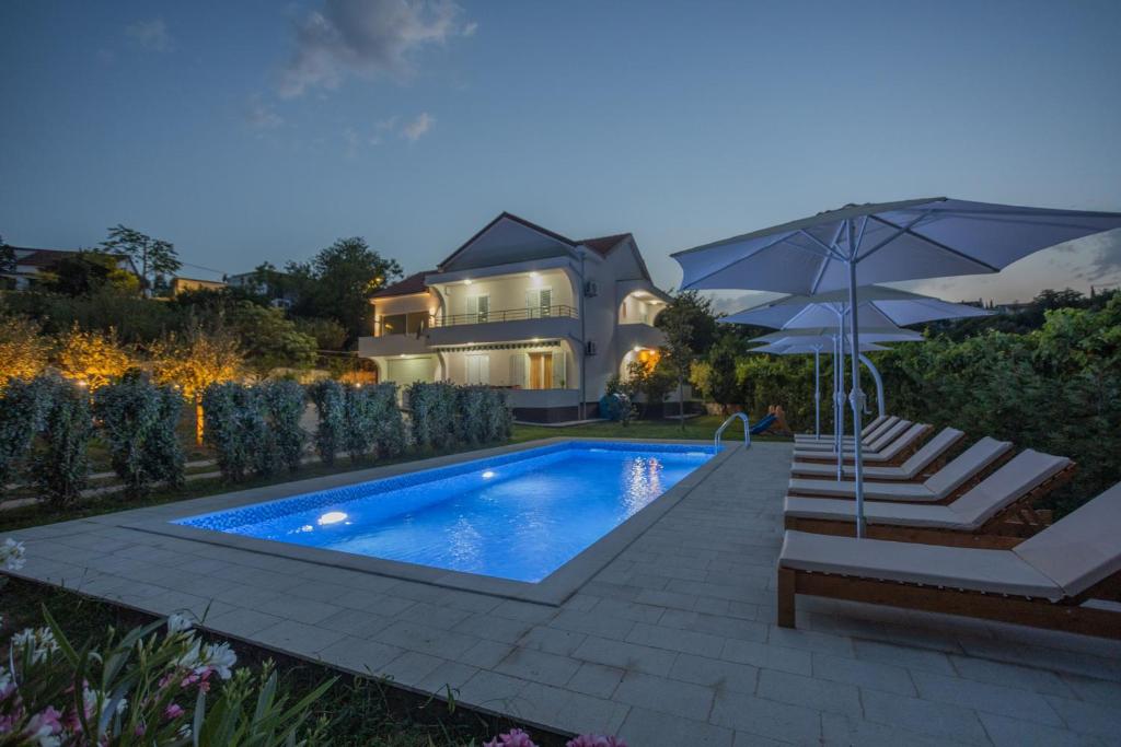 赫尔采格诺维Villa MontAnja的一个带遮阳伞和房子的游泳池