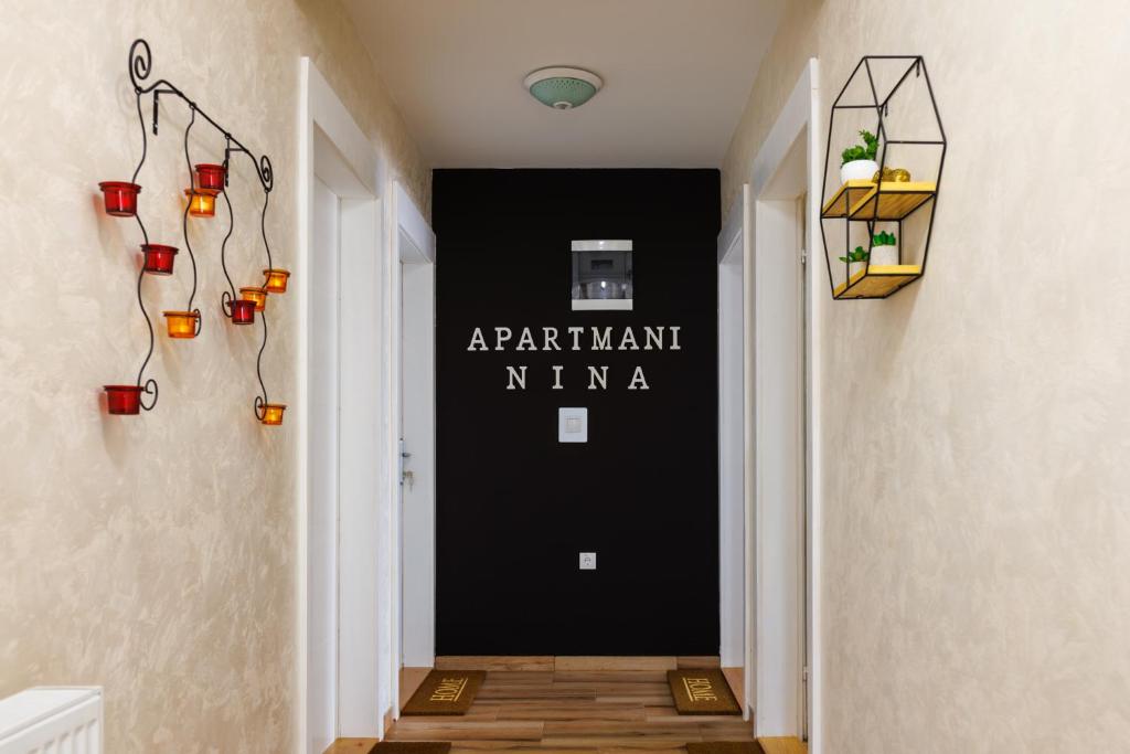 哥鲁拜克Apartmani Nina的走廊上设有黑色的墙壁,上面有标志