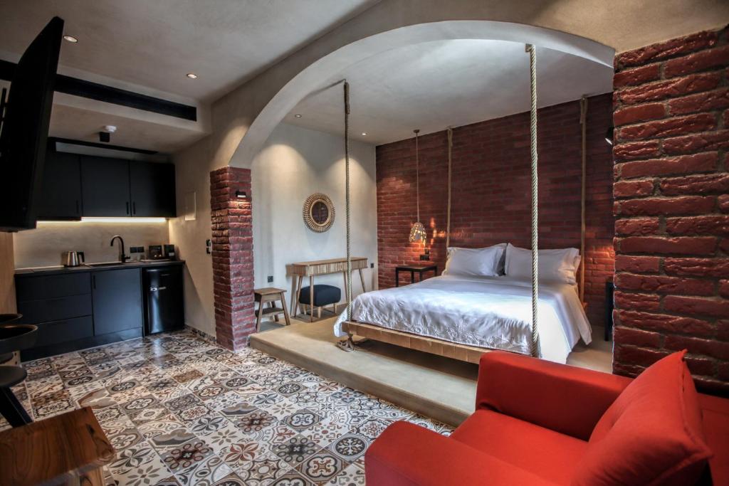 卡兰巴卡Meteora Heaven and Earth Kastraki premium suites - Adults Friendly的一间卧室配有一张床和一张红色的沙发