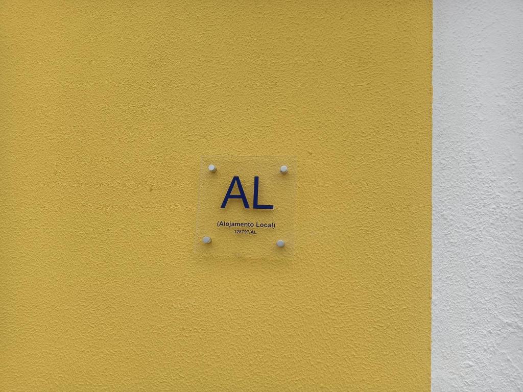 圣地亚哥-杜卡森Alojamento Local Largo da Igreja的黄色墙上的标牌,写着字母