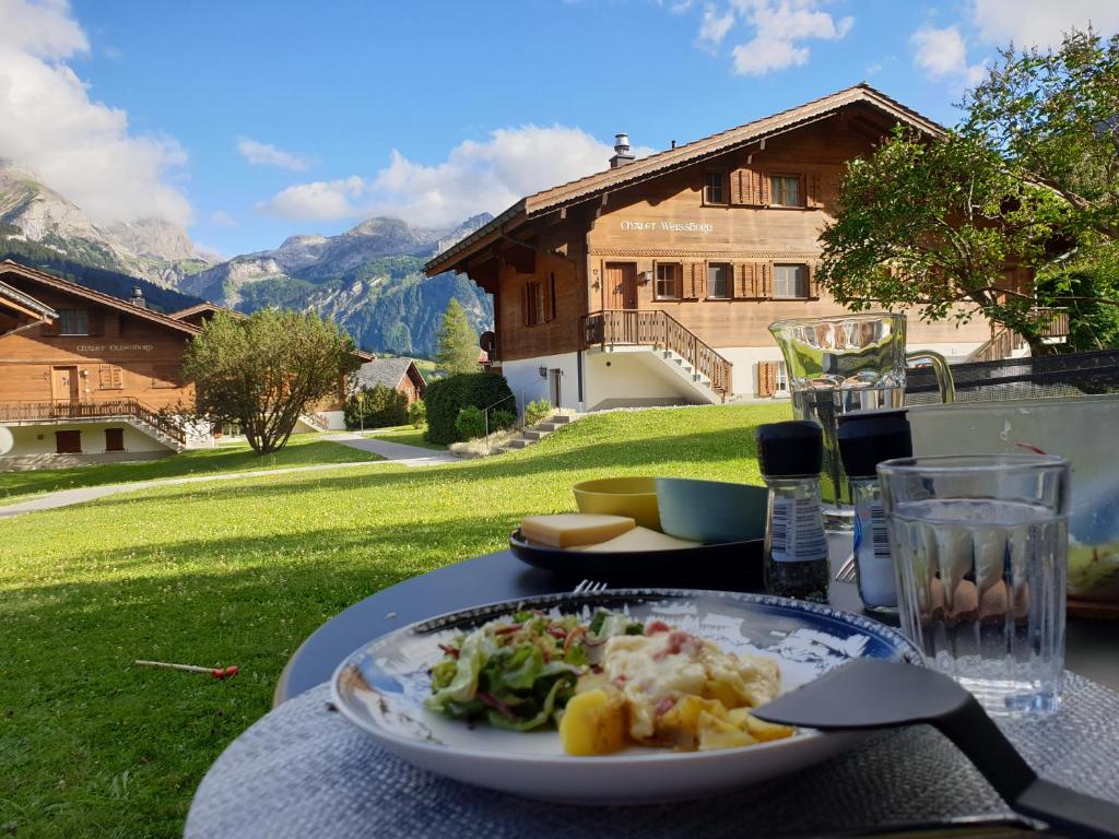 GsteigChalet Spitzhorn - Your Peak Getaway - Private Terrasse & gratis Parkplatz的一张桌子,上面有盘子的食物,还有房子