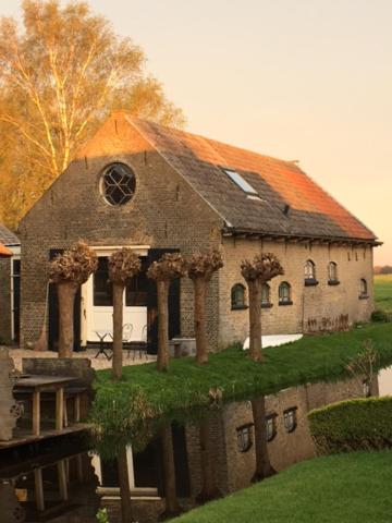 StolwijkB&B De Beijersche Stee, Logies aan de Waterkant的一座大型砖砌建筑,屋顶橙色