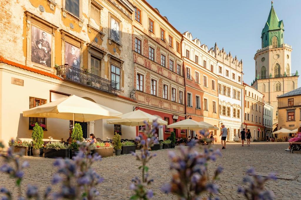 卢布林Rynek 10 Apartments的一条城市街道,街道上设有桌子和遮阳伞,建筑