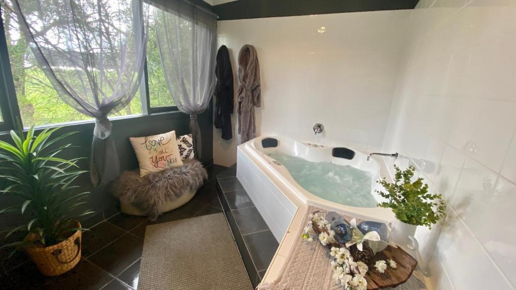 卡尔斯Couple's Resort Spa Retreat的一间带椅子和植物浴缸的浴室