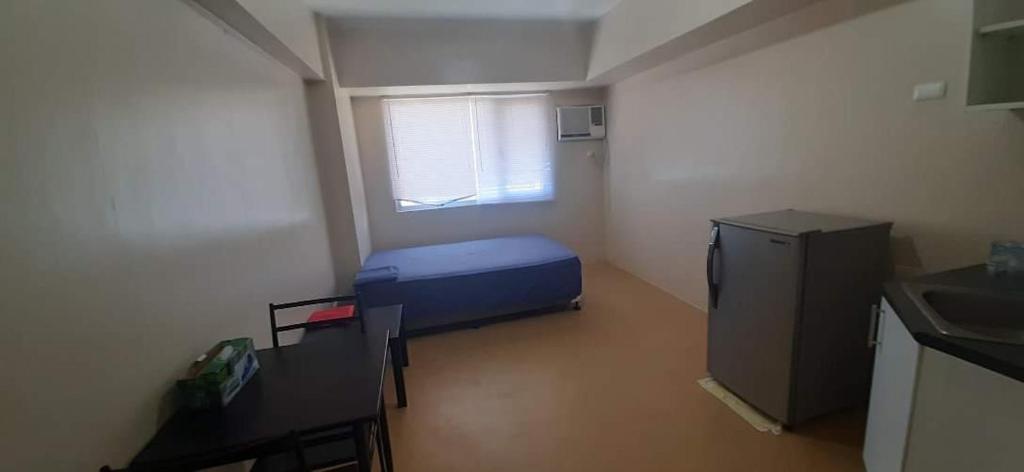 伊洛伊洛A’s Condo的小房间设有蓝色的床和窗户