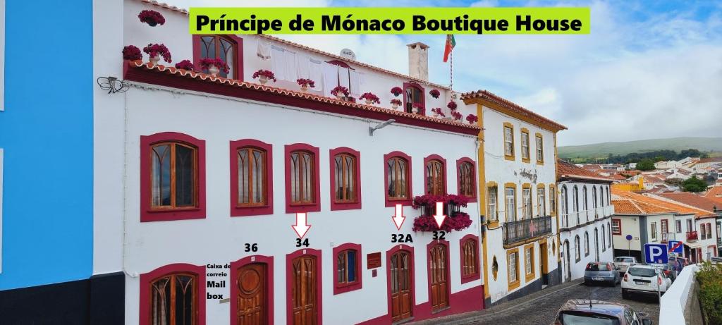 英雄港Príncipe de Mónaco Boutique House的白色的建筑,有红色的门窗