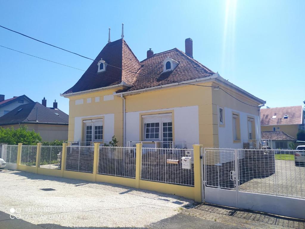 凯斯特海伊Villa Vanília的围栏后面的黄色和白色房子