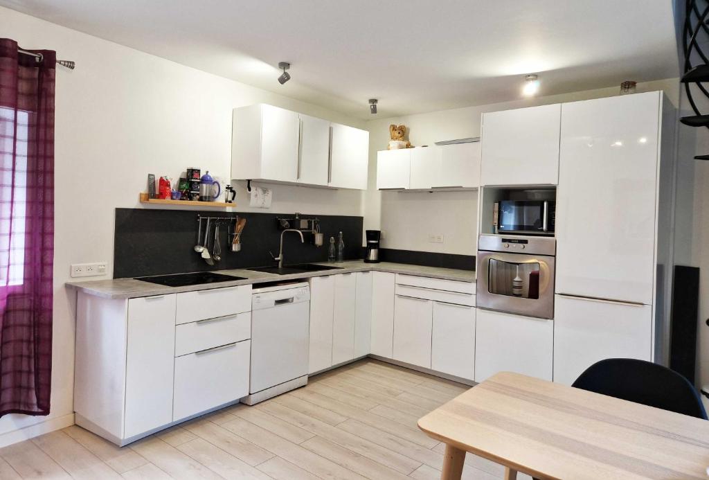 Vendegies-sur-ÉcaillonStudio, chambres, appartement, gite的白色的厨房配有白色的橱柜和桌子