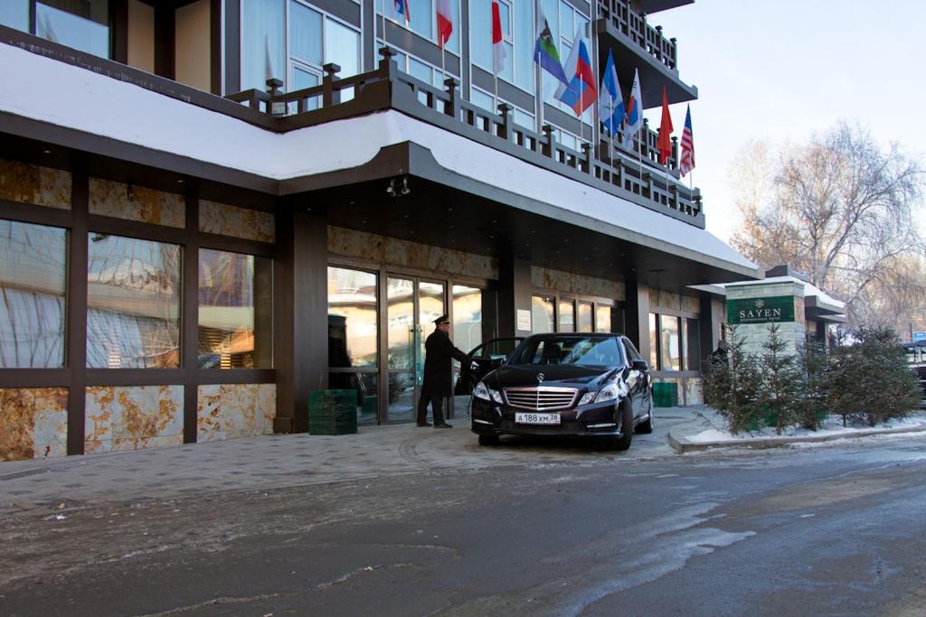 伊尔库茨克塞廷国际酒店的站在建筑物外,把车停在外面的人