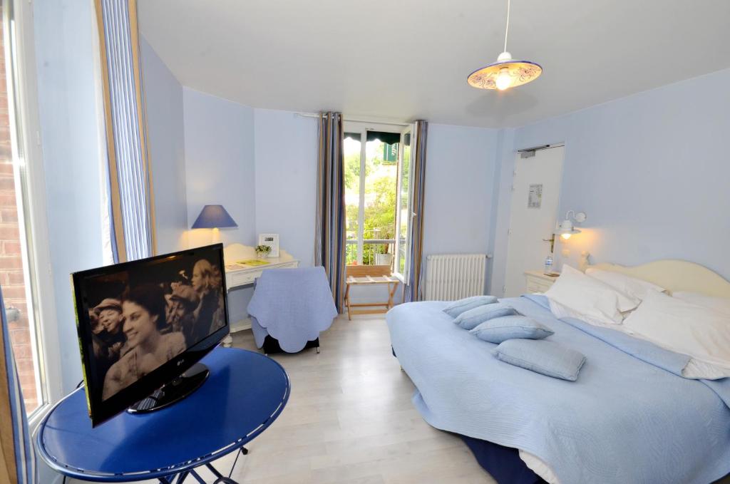 米隆拉沙佩勒Logis Hôtel De La Chapelle的一间卧室配有一张床和一张桌子上的电视