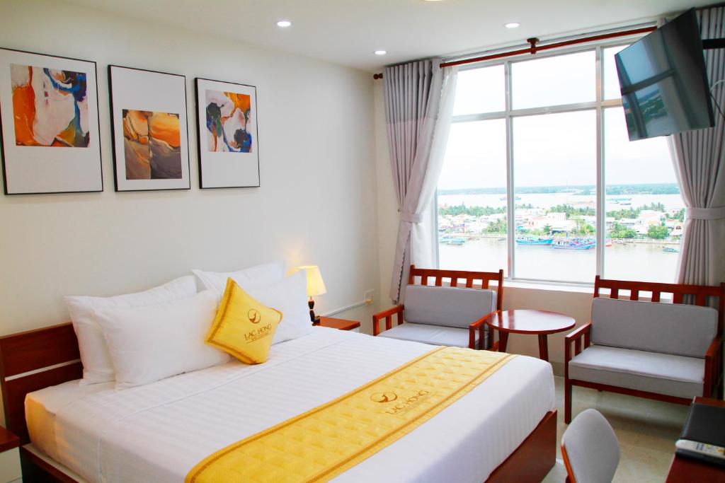 美寿Khách Sạn Lạc Hồng Mỹ Tho - Lac Hong My Tho Hotel的酒店客房设有一张床和一个大窗户