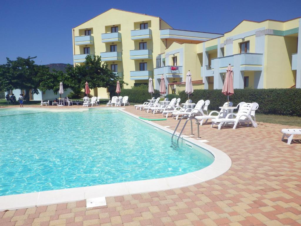 博萨伊索拉罗萨酒店的一座带椅子和遮阳伞的游泳池位于一座建筑旁边