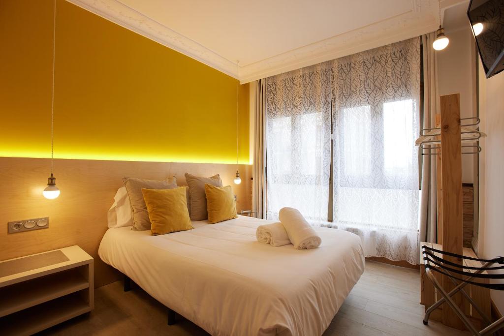 圣塞瓦斯蒂安Pensión Aia的卧室配有白色床、黄色墙壁和窗户