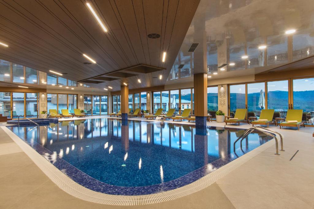 特里亚夫纳Wine & SPA Hotel Chukara的酒店大堂的大型游泳池,配有椅子