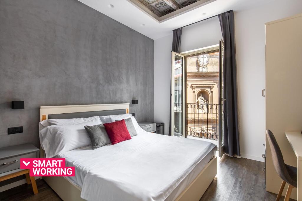 巴勒莫Villena Plaza的一间卧室配有带白色床单和红色枕头的床。