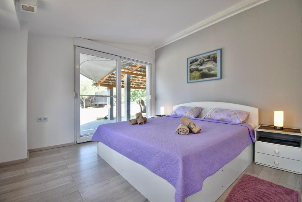 罗波里卡Peaceful oasis family holiday house的一间卧室配有一张紫色床,上面有两只泰迪熊