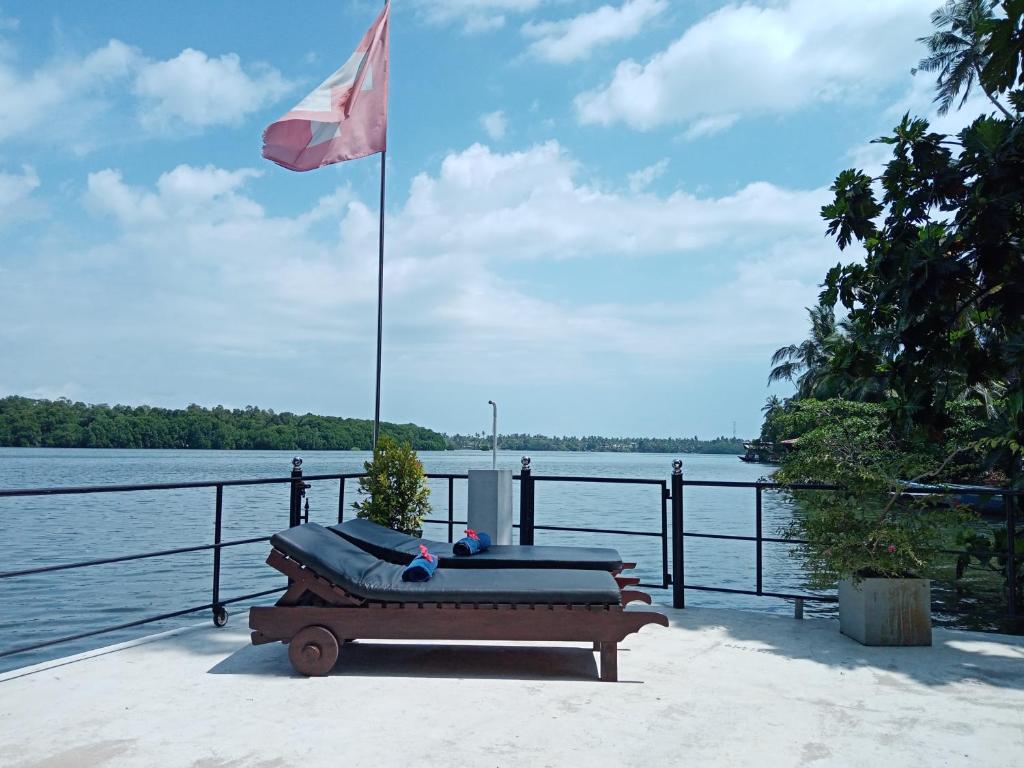 阿鲁特伽马Villa Bentota River View的水体旁挂着旗帜的长凳