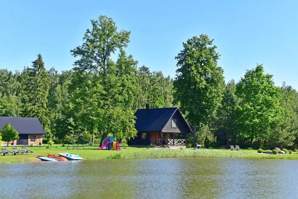 DūdorynėVila Loreta - namelis su pirtimi的湖岸上的小屋,有两艘船