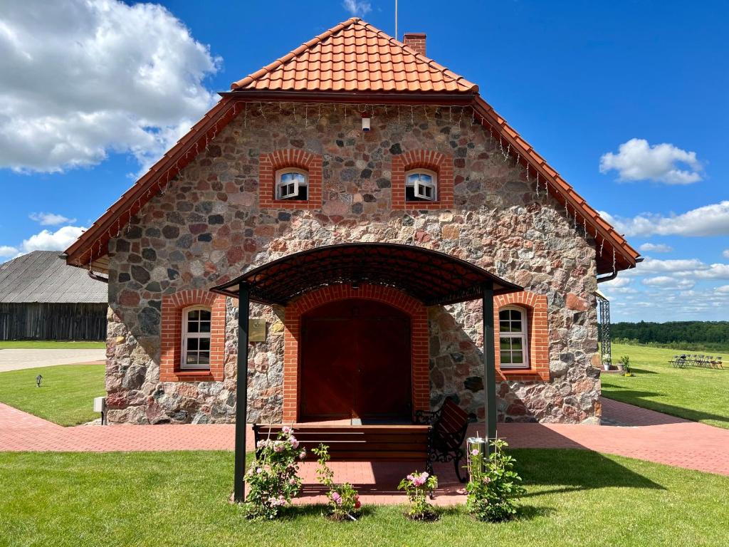 KelmėPakėvio dvaras - Pakevis manor的草上有一扇大门的小石头建筑