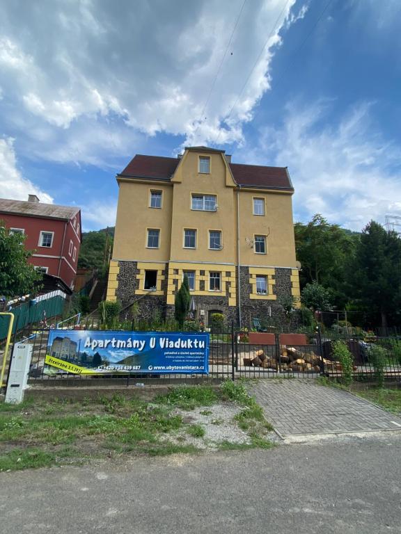 拉贝河畔乌斯季Apartmány U Viaduktu 46的一座黄色的大建筑,前面有标志