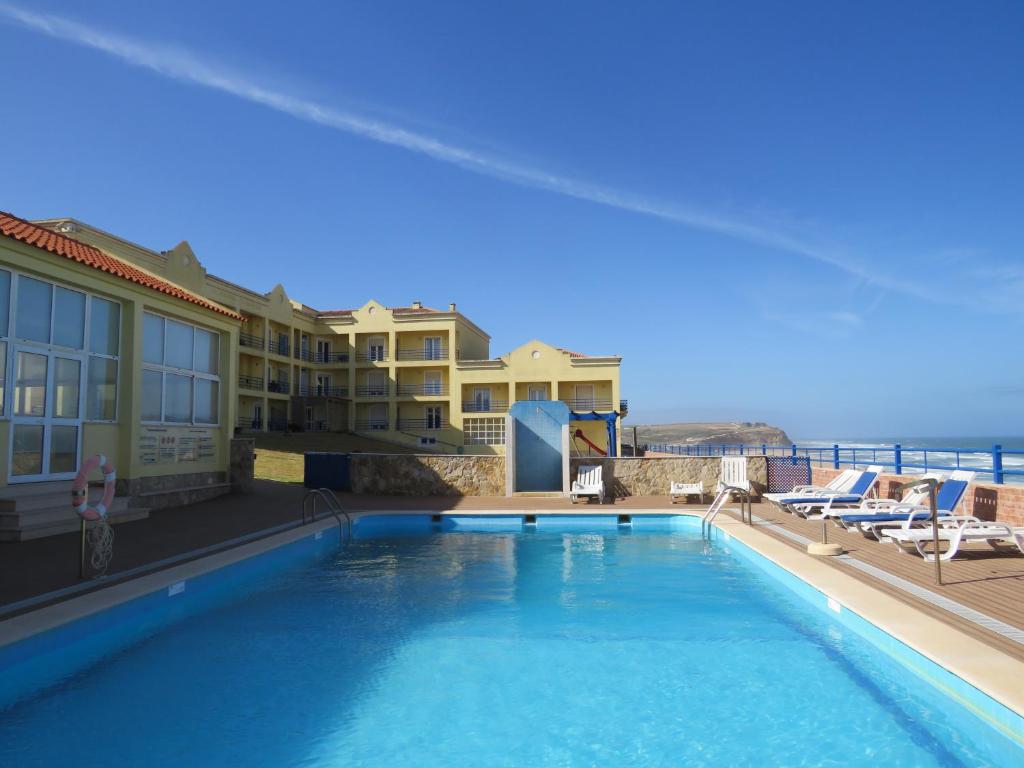 西尔维拉Hotel Apartamento Praia Azul的一座大型游泳池,毗邻一座建筑和大海