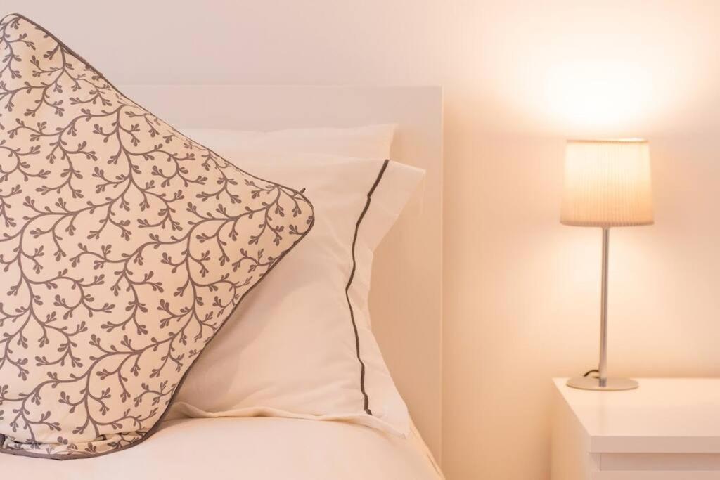 滨海克拉克顿New stylish 4 bed house moments from Clacton beach的枕头坐在床头灯旁的床上