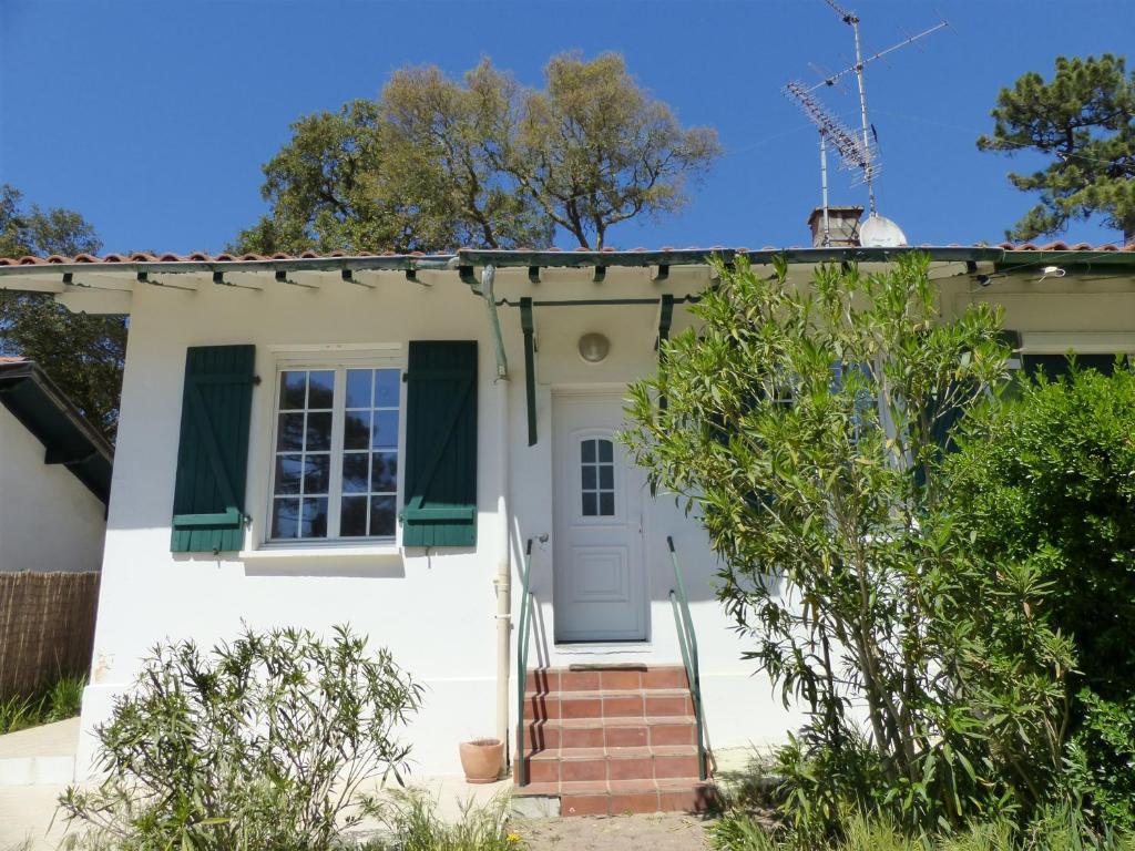 奥瑟戈尔Villa Mitoyenne Pour 4 Personnes Proche Centre-Ville D hossegor的白色的房子,有绿色百叶窗和门