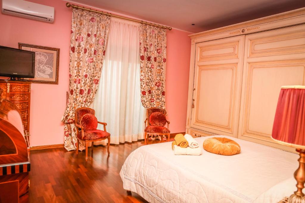 Guardia SanframondiIL Tetto Di Guardia的卧室设有粉红色的墙壁和一张床及椅子