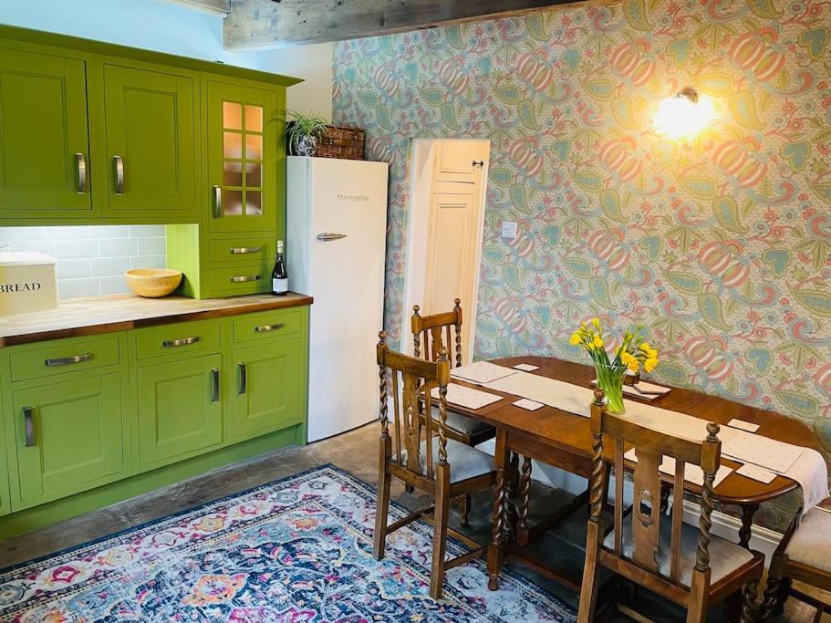 哈沃斯Tipple Cottage的厨房配有绿色橱柜、桌子和冰箱。