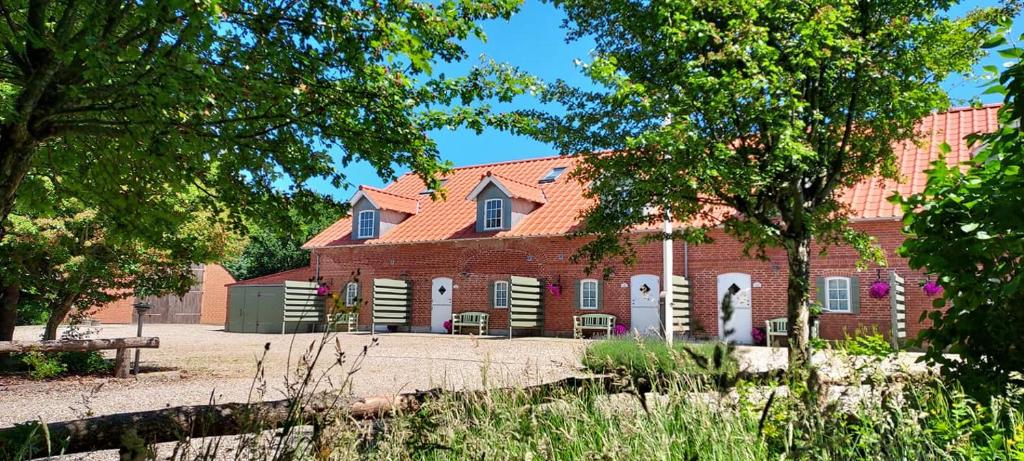 里伯Lustrup Farmhouse的一座大型红砖建筑,前面有树木