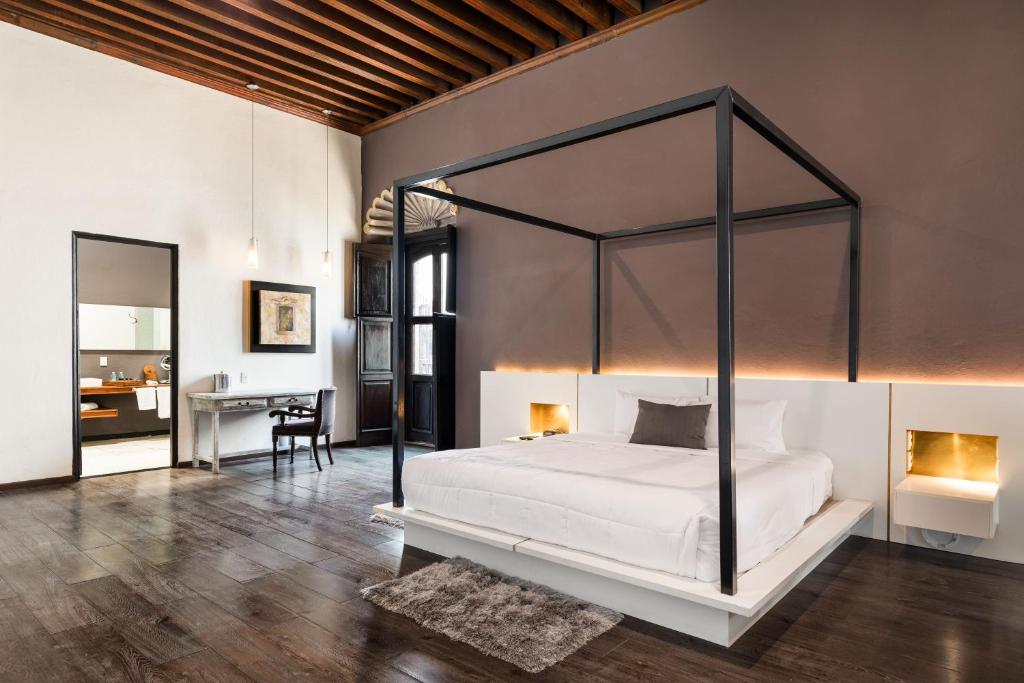 克雷塔罗El Mesón de Santa Rosa的一间卧室配有一张天蓬床和一张书桌