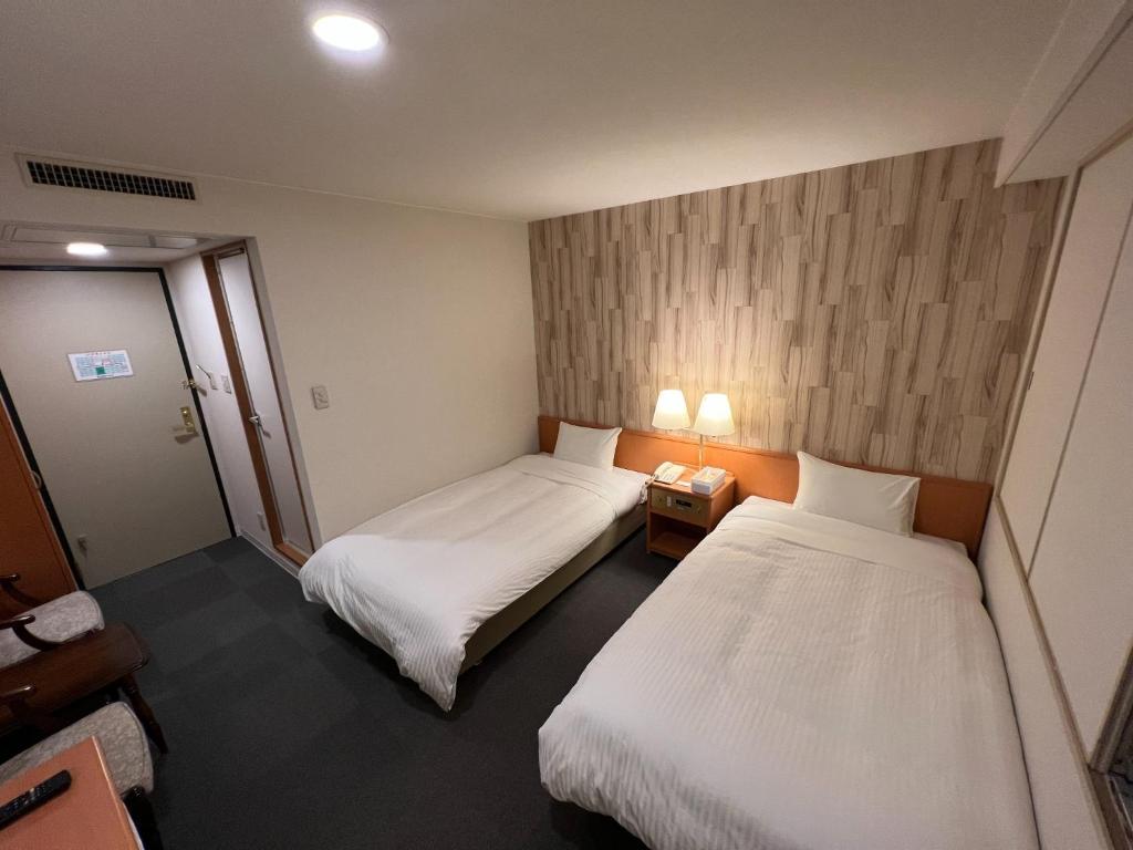 北见Kitami Daiichi Hotel - Vacation STAY 73148v的酒店客房设有两张床和两盏灯。