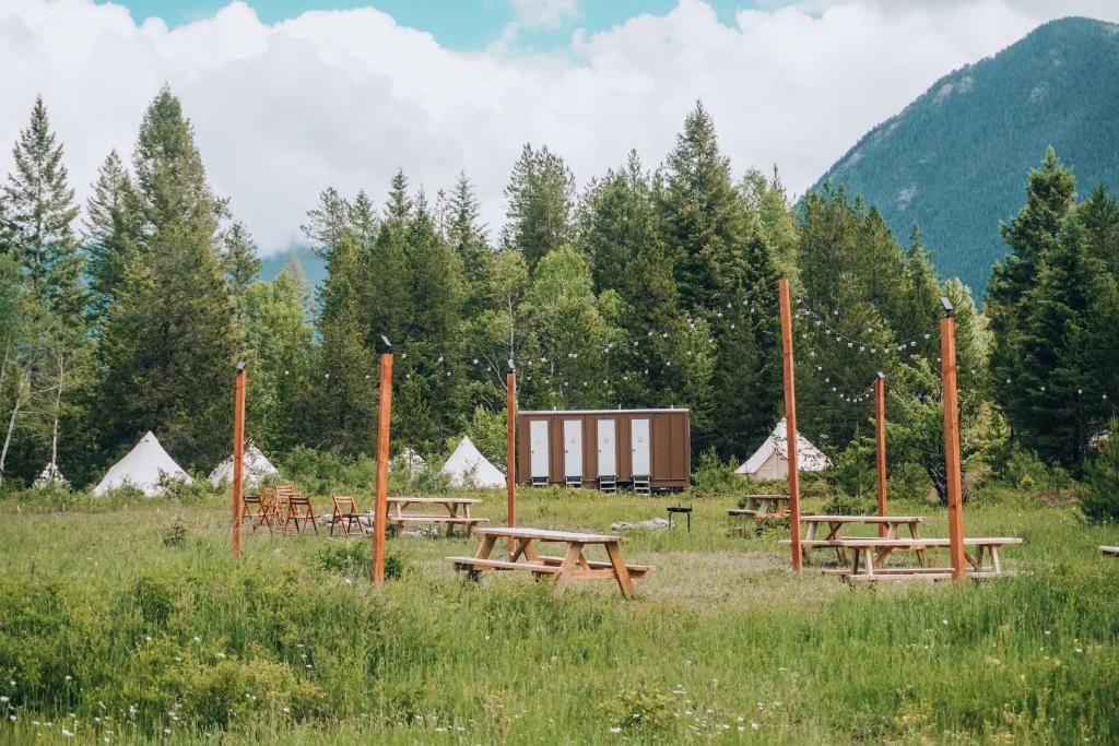 CoramWander Camp Glacier的一组野餐桌,位于一个有帐篷的场地内