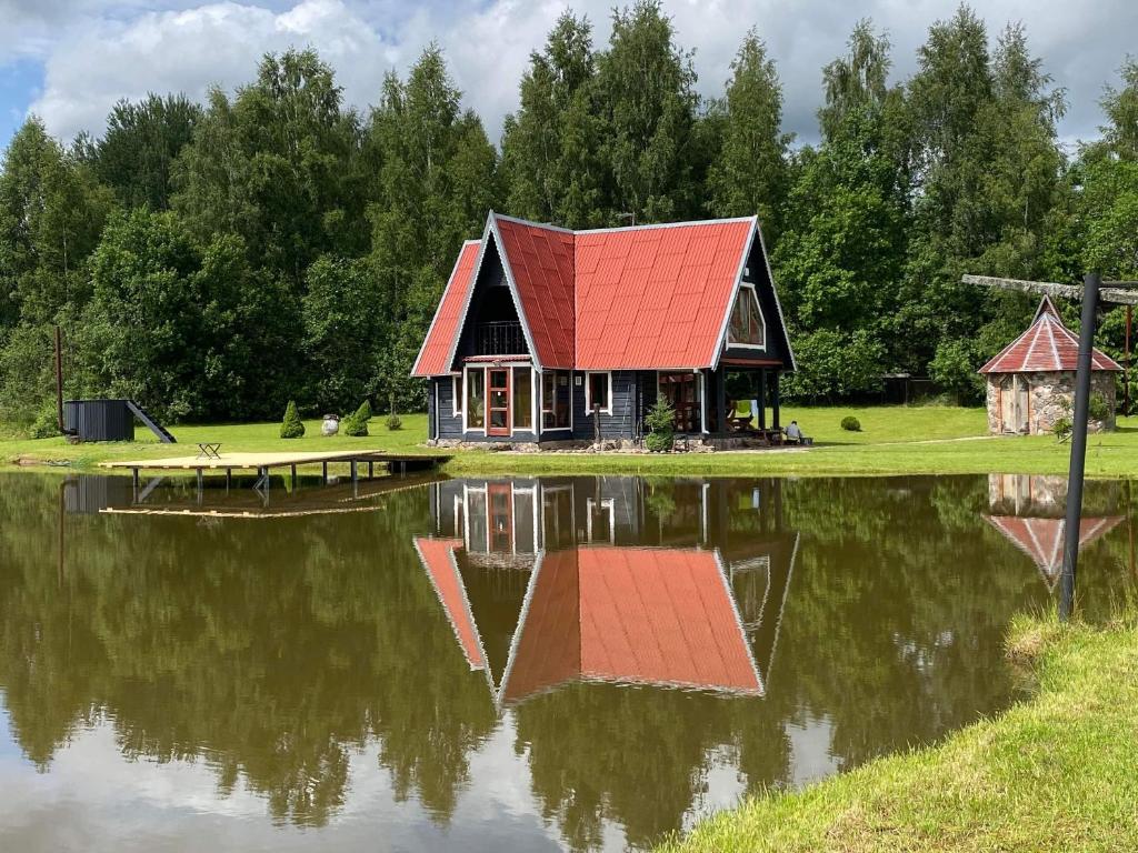 阿尼克什奇艾Sodyba Anykščių raj.的一座位于湖面上,有红色屋顶的房子