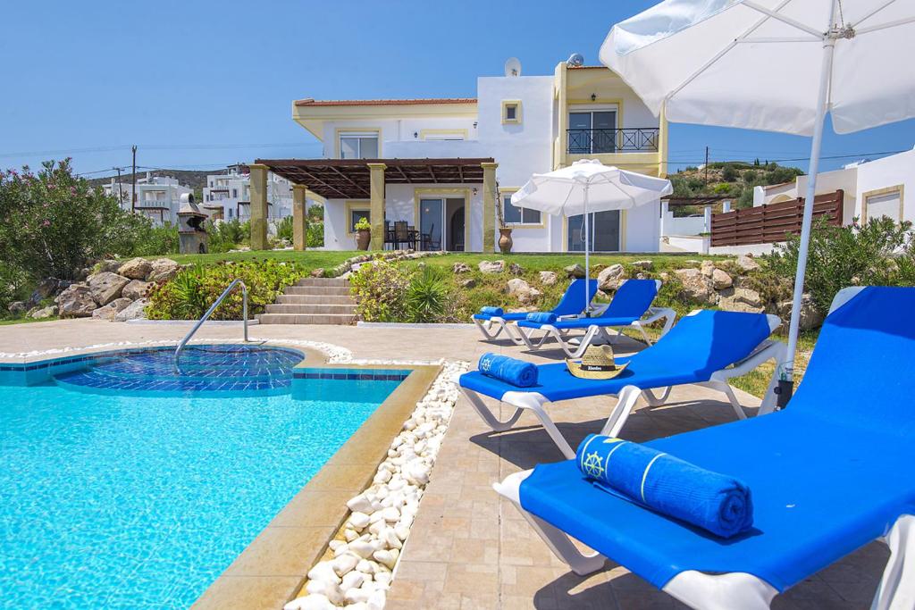 卡拉索斯阿列克谢别墅的一座房子旁的游泳池,配有蓝色的椅子和遮阳伞