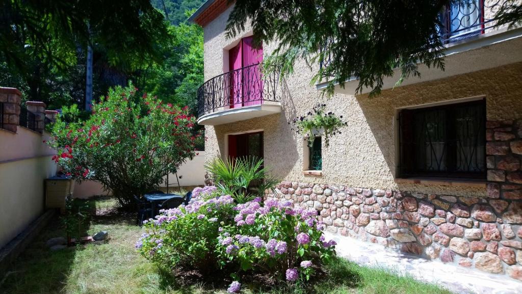 韦尔内莱班Appartement 48 m2 avec jardin au rdc dans villa à 5 min à pied des Thermes de Vernet-les-Bains, location de samedi à samedi的一座带粉红色窗户和一些鲜花的房子