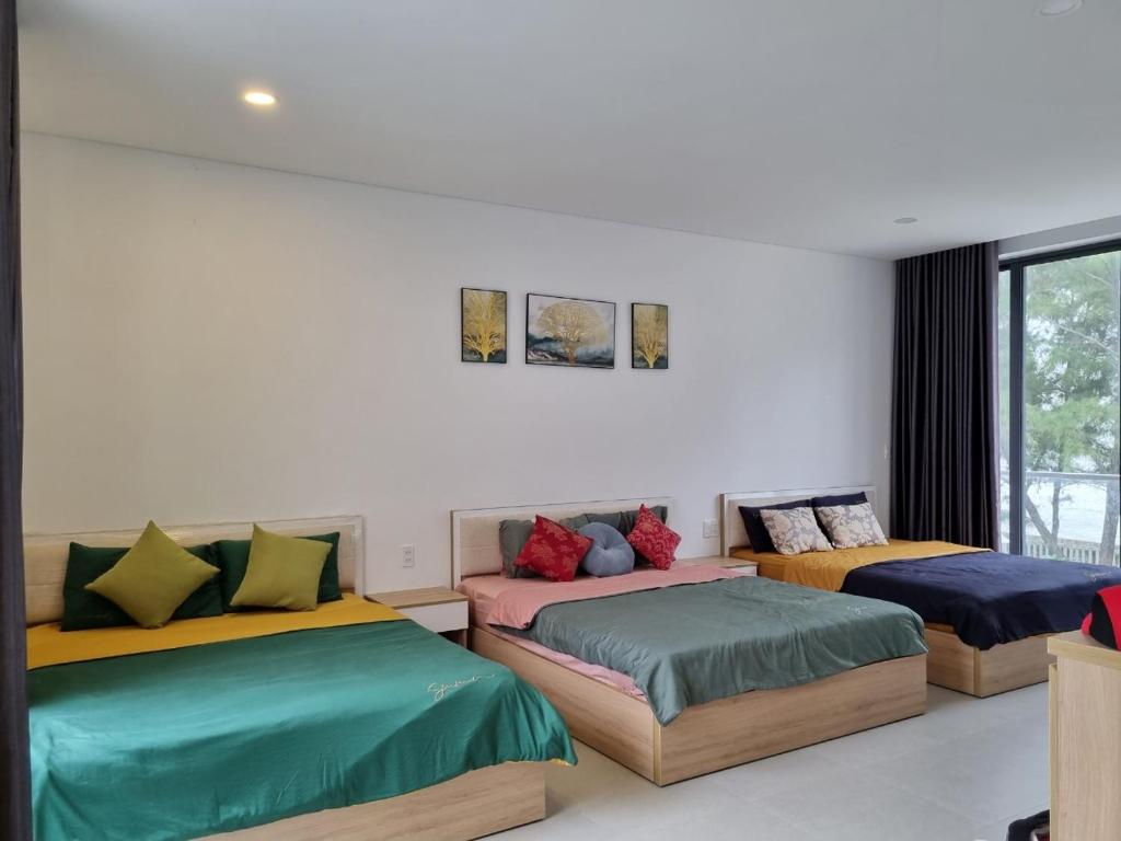 隆海Villa Zenna Long Hải - Mimosa 611 View Biển的客房内的两张床和色彩缤纷的靠垫