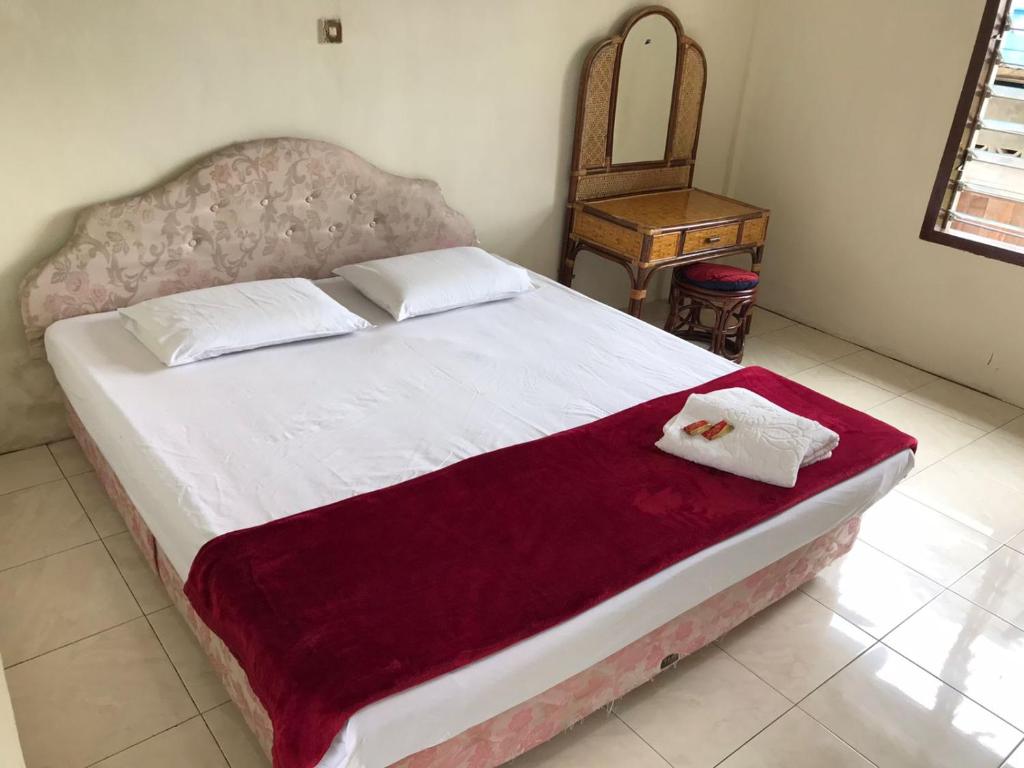 不拉士打宜Hotel Miranda at Desa Wisata Berastagi的一间卧室配有一张大床和一把椅子