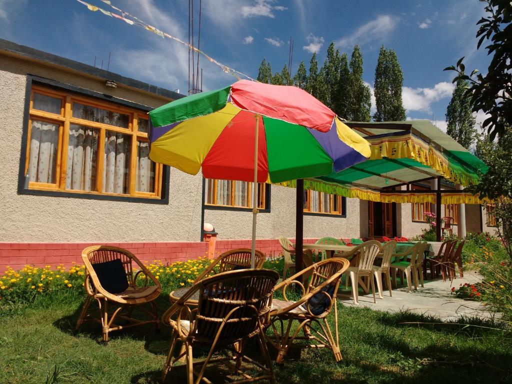 列城Rabyang Guest House and Homestay的一张桌子和椅子,配有五颜六色的雨伞